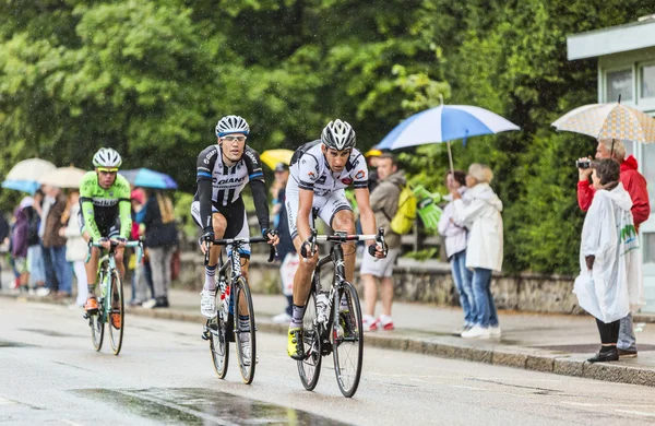 Three Cyclists Riding in the Rain