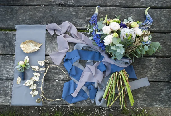 Bouquet of beautiful flowers and brides accessories on wooden surface