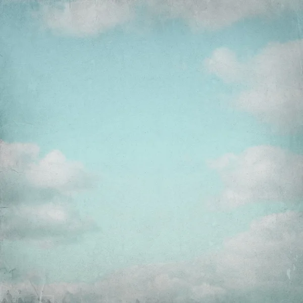 Old paper background with blue sky and white clouds in grunge style.