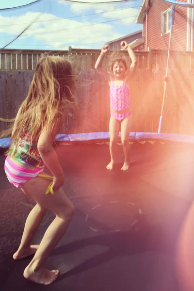 Children jumping on a trampoline in back yard