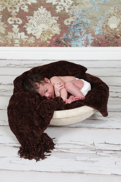 Baby boy sleeping on brown blanket