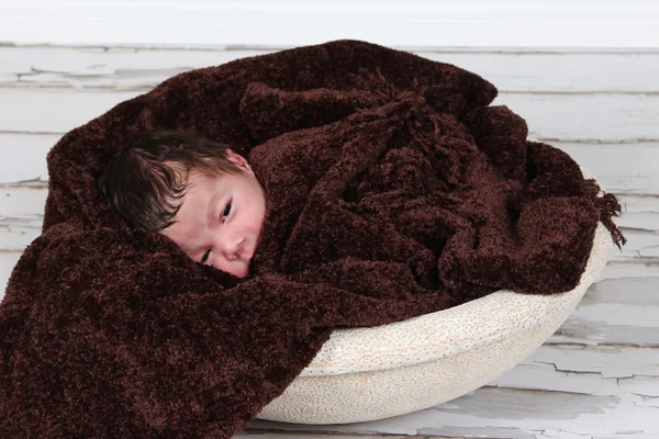 Baby boy sleeping on brown blanket