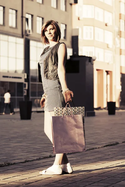 Happy young fashion woman with shopping bags on a city street