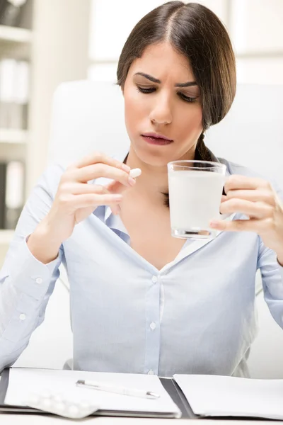 Young Woman Takes A Pill At Work