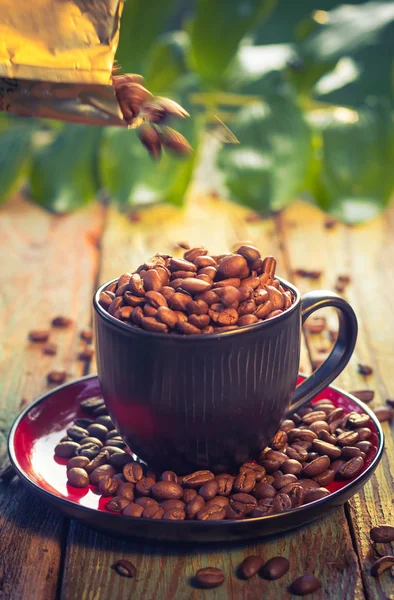 Brown beans pouring coffee cup