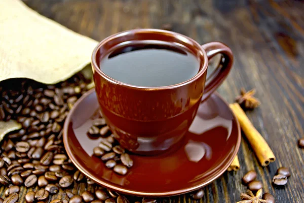 Coffee in brown cup with cinnamon and bag on board