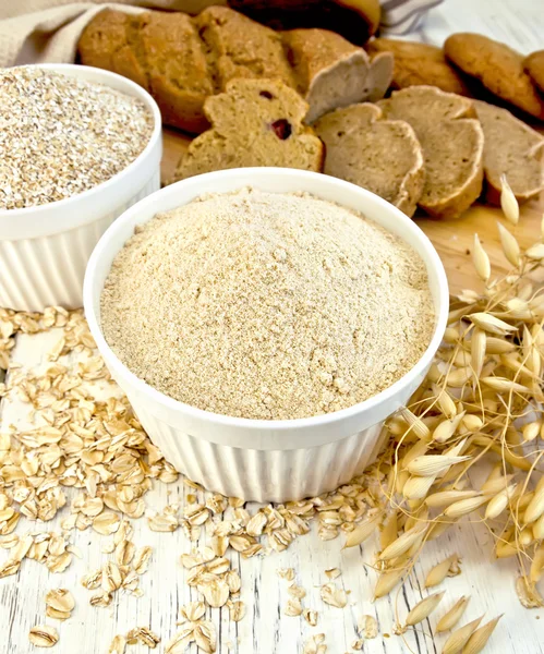 Flour oat and bran in white bowl with bread on board