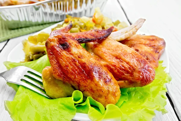 Chicken wings fried with salad in plate on board