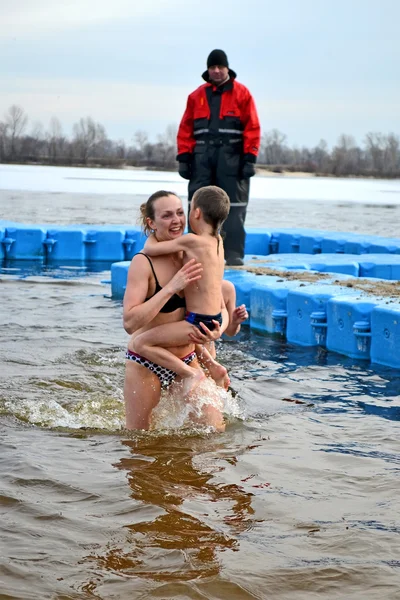 Woman with kid in cold water, Epiphany in Kiev, Ukraine.