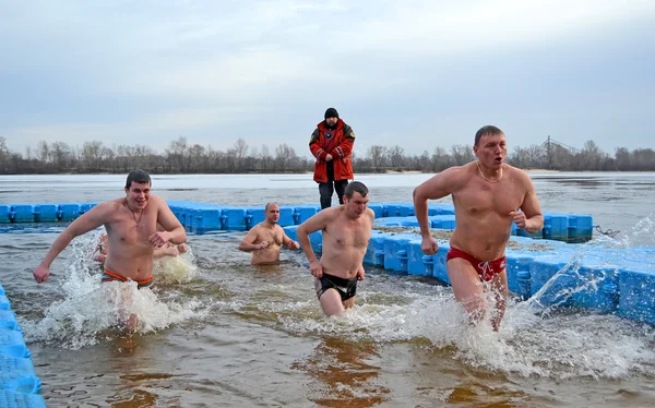 Man group running in cold water, Epiphany in Dnieper river in Kiev, Ukraine.