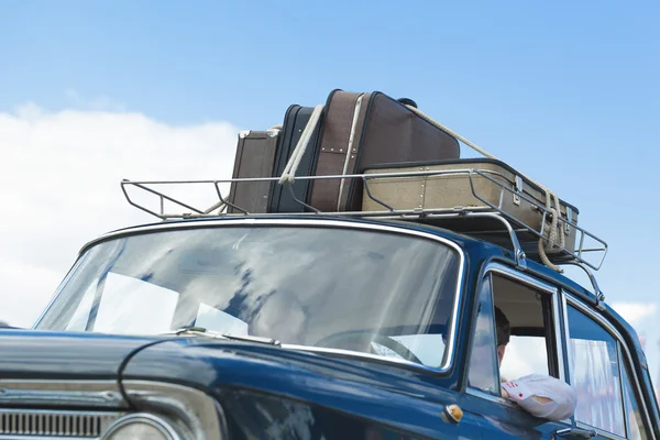 Suitcases on the roof of the trunk of a car.