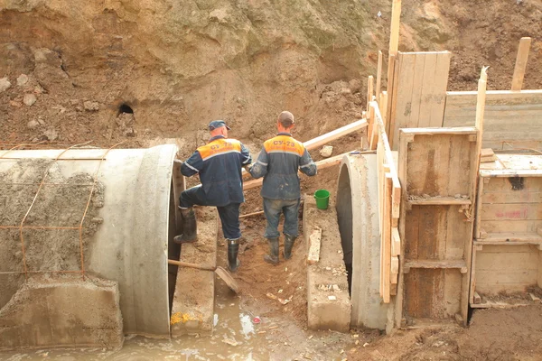 Workers laying collector concrete pipes