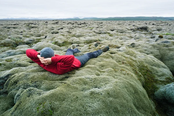 Man is a traveler on moss on a lava field in Iceland