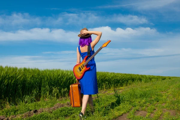 Young woman with suitcase and guitar