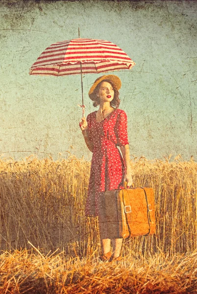 Young woman with umbrella and suitcase
