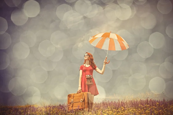 Young woman with umbrella, camera and suitcase