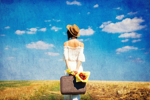 Young woman with suitcase and bouquet