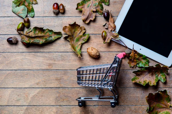 Tablet, shopping cart and fallen leaves