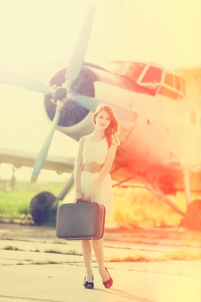 Lonely girl with suitcase at near airplane.