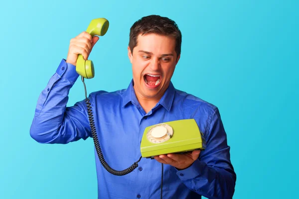 Surprised man in shirt with telephone on blue background.