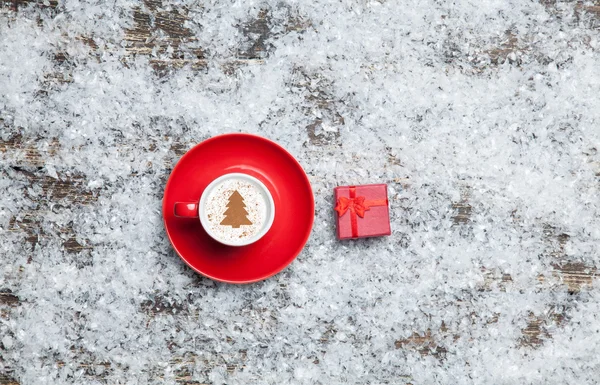 Cappuccino with christmas tree shape and gift box on artificial