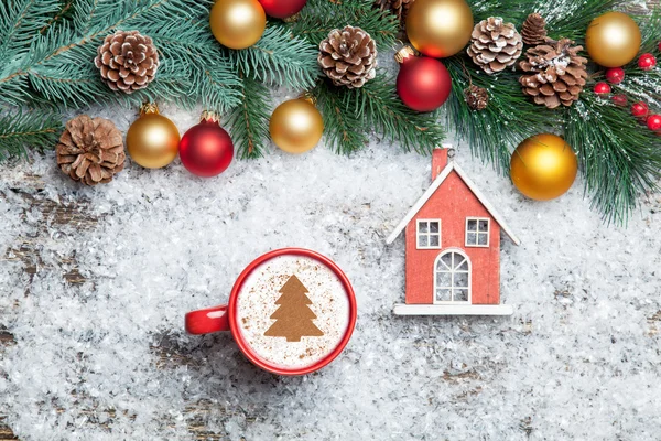 Cappuccino with christmas tree shape and toy home on artificial