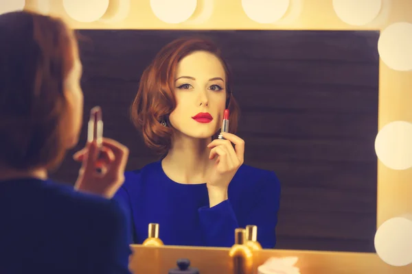 Portrait of a beautiful woman as applying makeup near a mirror