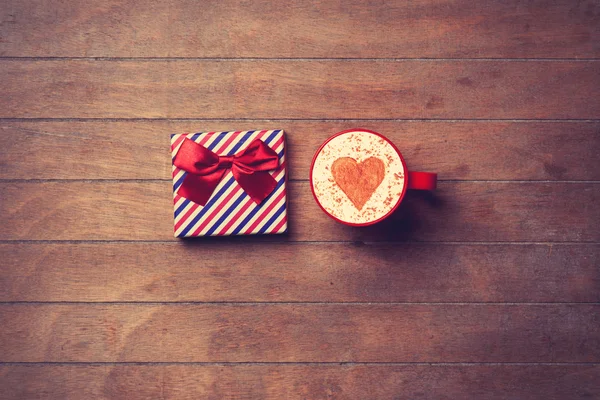 Cup and gift box on wooden background