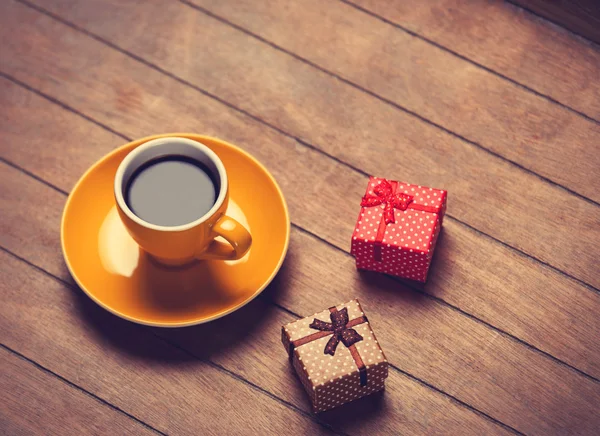 Cup of coffee and gift boxes on a wooden table.
