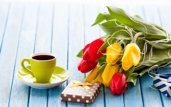 Cup and gift box with bouquet of tulips