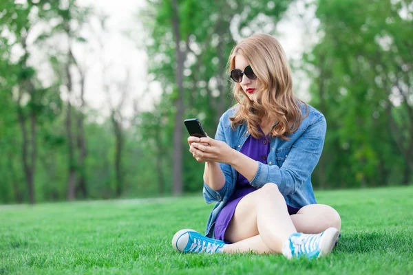 Girl with mobile phone on grass