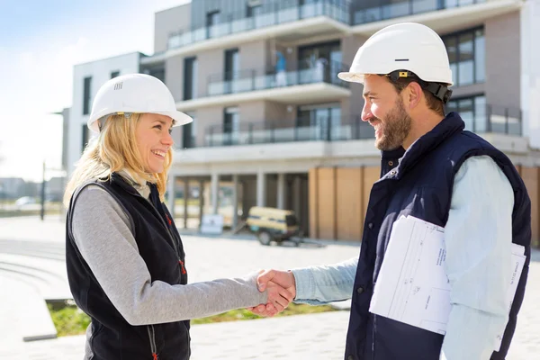 Architect and worker handshaking on construction site