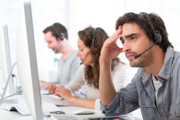 Young attractive man ill-at-ease at work