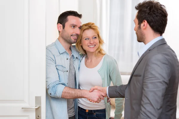 Young happy couple handshaking real estate agent after signing c