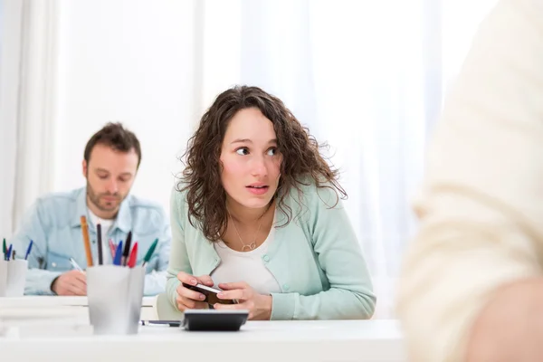 Young attractive woman cheating with mobile during exam