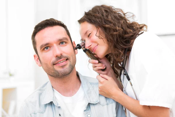 Young attractive doctor checking patient's ear