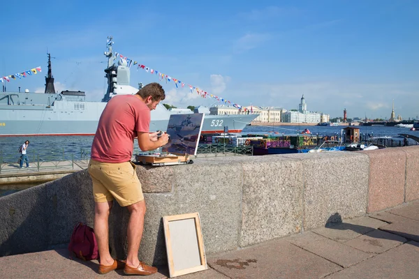 Artist paints a picture with a military ship on the Admiralty embankment in Saint Petersburg