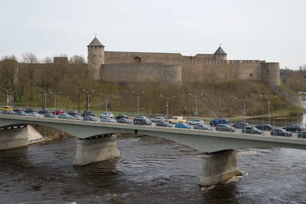 Border crossing bridge between Russia and Estonia through the Narva river on the background of the Ivangorod fortress, cloudy day