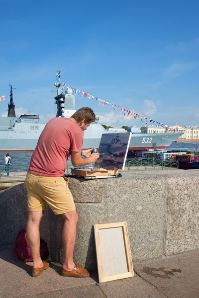 The Artist paints a picture with a military ship on the Admiralty embankment in Saint-Petersburg