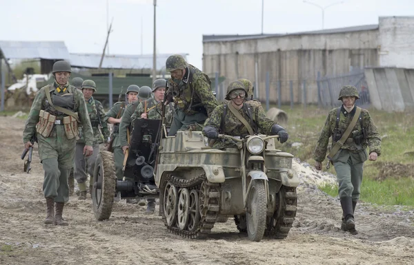 A group of German soldiers with the tractor SdKfz 2 and guns moving along the road. Reconstruction episode of the great Patriotic war