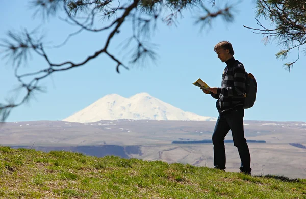 Tourist with a map and a backpack on a background of mount Elbru