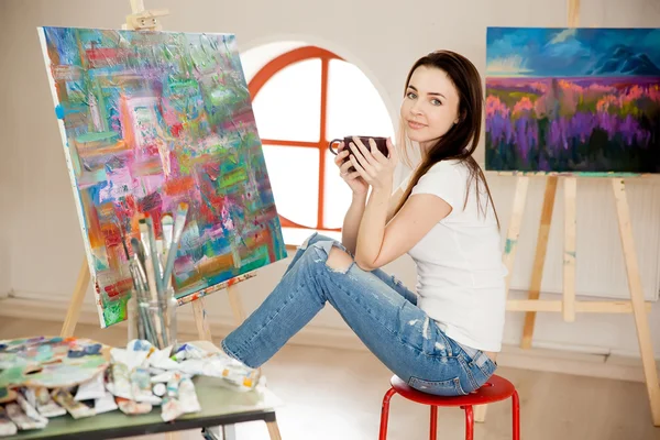 Female Artist Working On Painting In Studio