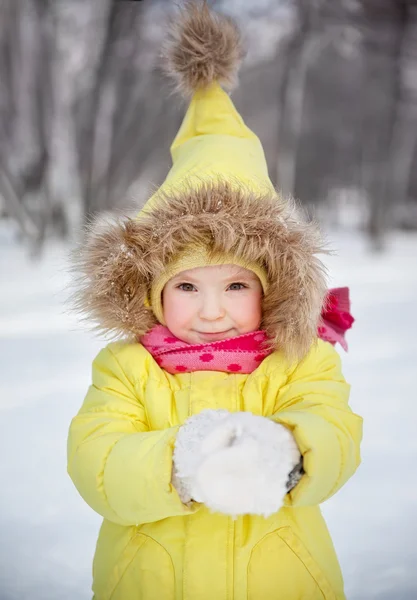 Funny little girl in winter clothes in a snowy forest