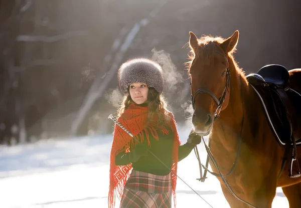 Beautiful young woman and horse in winter forest