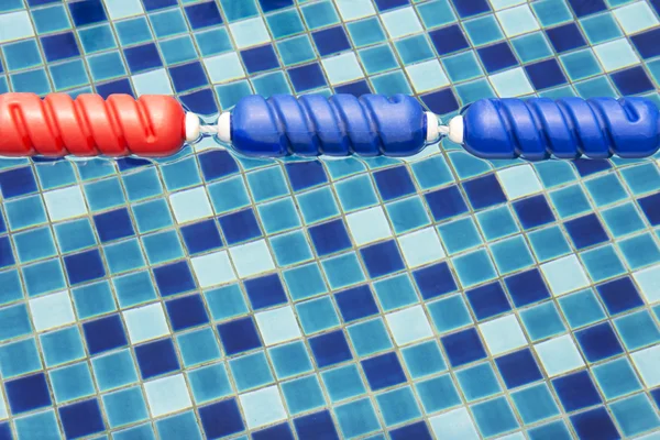 Blue and red colors plastic swimming pool lane divider and rope floating on water surface