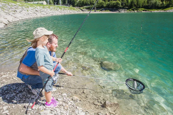 Dad and daughter fishing together a trout in a mountain lake