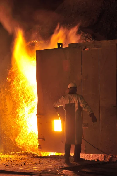 Steel worker takes a sample from oven