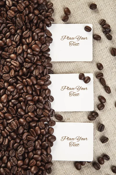 Three blank white card  on textile and coffee beans  background