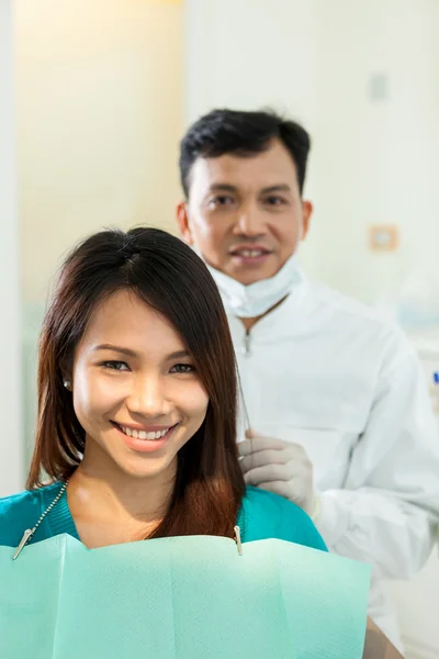Portrait of dentist with his patient looking towards the camera