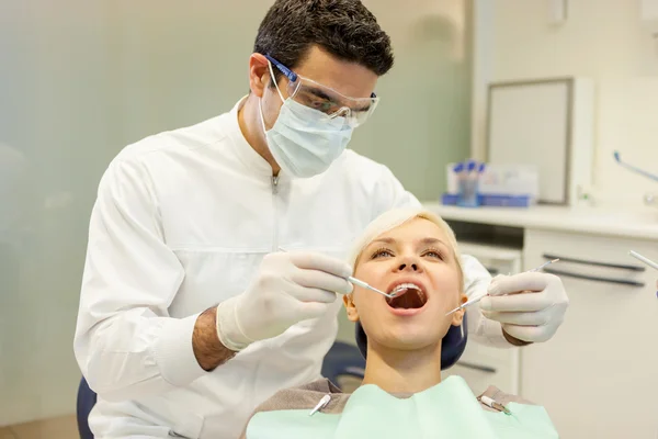 European dentist is doing a checkup on a young blonde woman